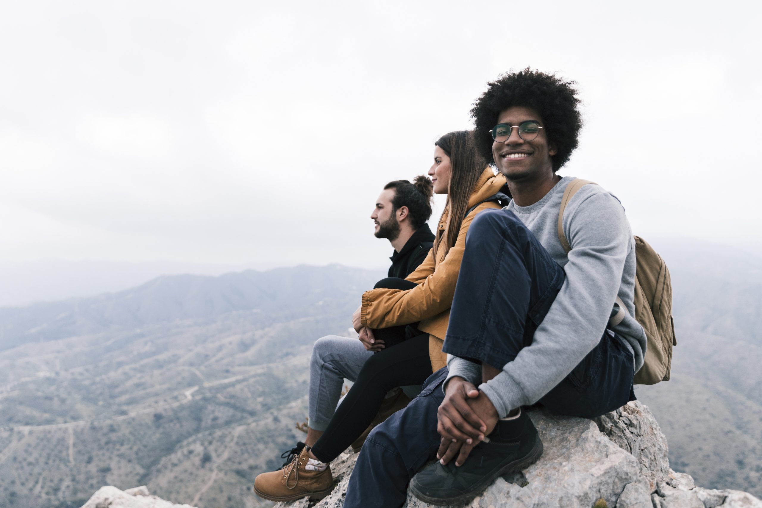 portrait-smiling-man-sitting-top-rock-enjoying-with-his-friend